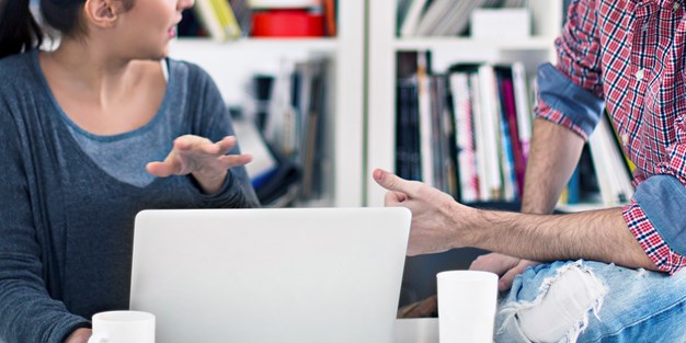 En man och en kvinna som diskuterar vid en dator. Foto