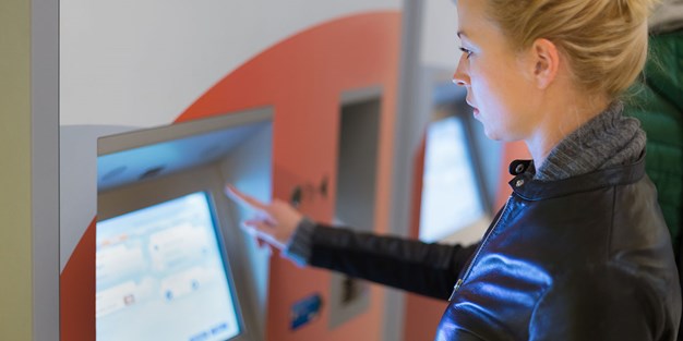 En person som använder en biljettautomat. Foto