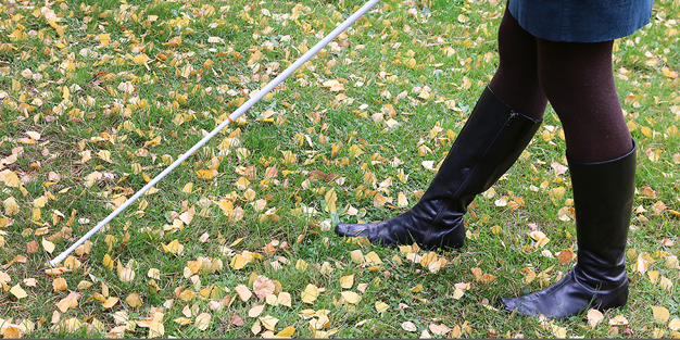En person som använder en vit käpp på en gräsmatta. Foto: Synskadades Riksförbund