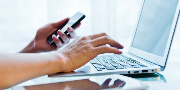 A person using a smartphone and a laptop. Photo.