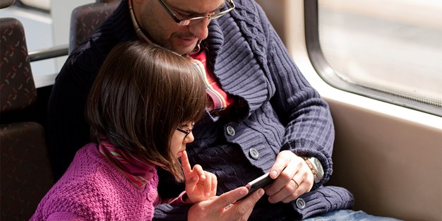 Far og datter avbildet på skjermen til en smartphone. Foto