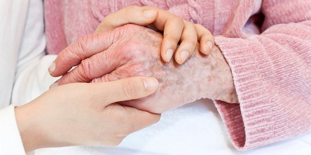 En ung persons hånd som holder hånden til en eldre person. Foto