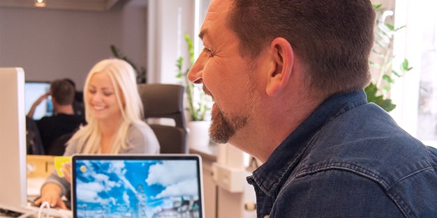 Jennifer och Johan på Funka som skrattar vid sina datorer. Foto