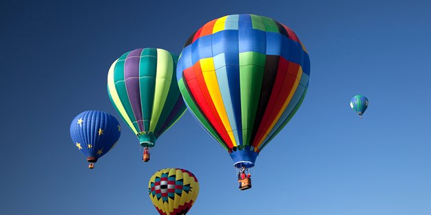 Flera varmluftsballonger uppe i luften. Foto
