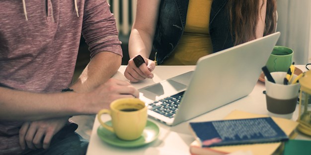 Två personer som sitter framför en laptop. Foto