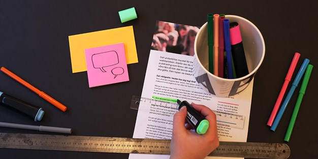 Hand som stryker under ett ord med grön penna på ett informationsblad. Foto