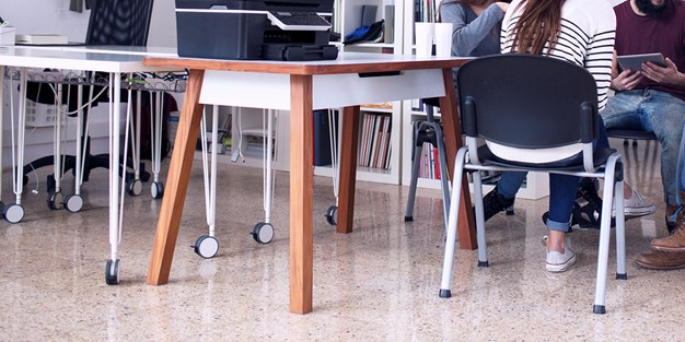 Persons working at a few tables. Photograph