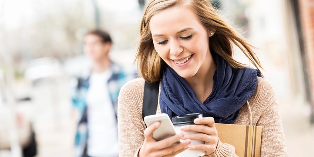 Young woman holding her mobile phone and laughing . Photo