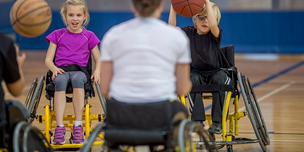 Children play basket ball in wheelchairs. Photo