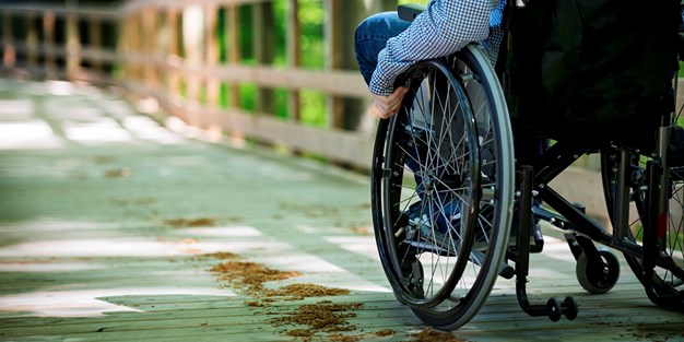 Person i rullstol på en väg. Foto