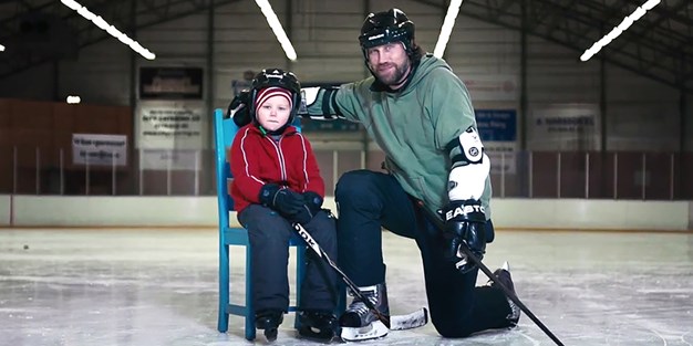Perter Forsberg på isen med ett barn i en blå stol bredvid. Foto