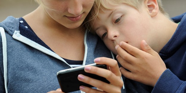A young girl and a boy using a smartphone. Photo