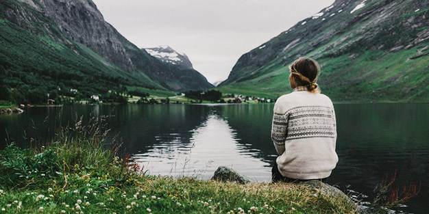 A person sitting by a mountain lake. Photo