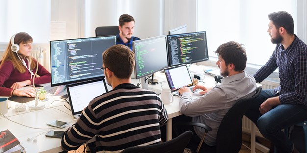 A team of web developers in front of their computers, photo.